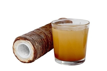 Section of pipe with iron accumulation next to a glass of yellow, brown water