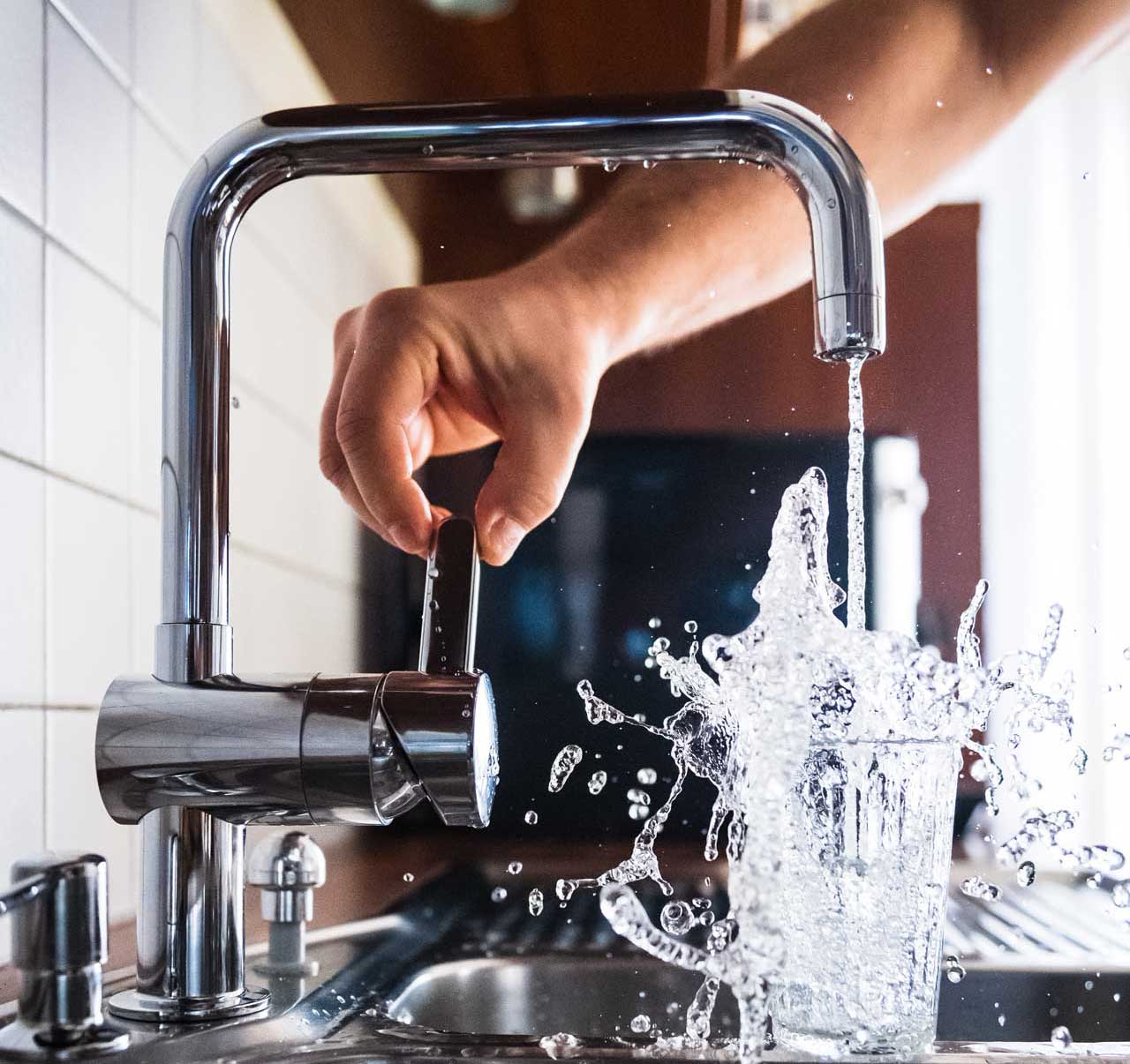 Fast pouring tap water from the faucet into a drinking glass