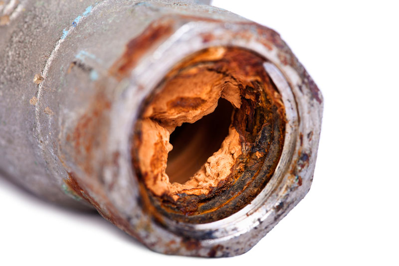 Cross-section view of a clogged home water pipe with rusty corrosion caused by the buildup of iron from water.
