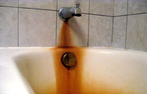 White bathtub with dark orange stains caused by iron in the water.