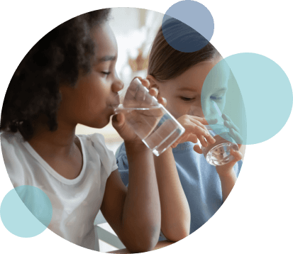 two children at a table drinking clean water from glasses