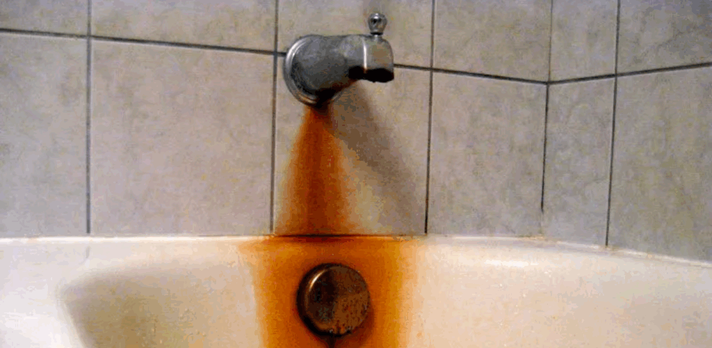 iron corrosion building up on tile under bathtub faucet