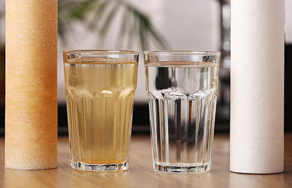  two glasses of iron water and clear water side by side with filters