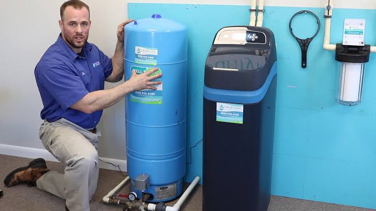 Carroll Water Technician next to a Ecowater constant pressure tank