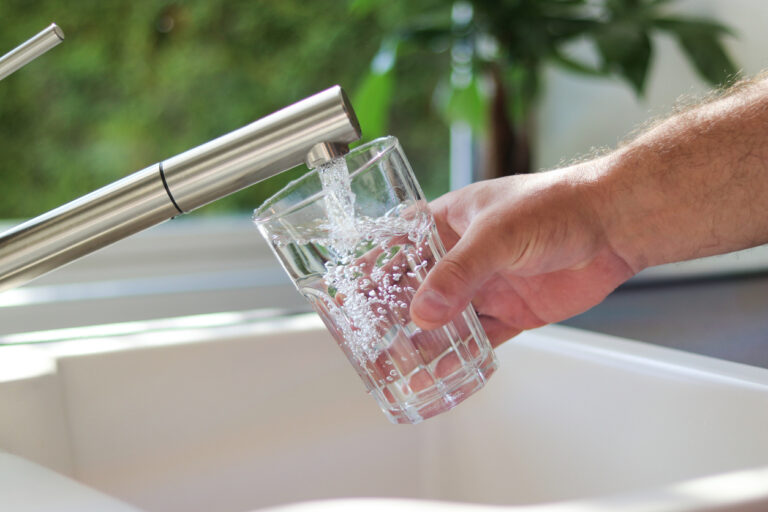 A person filling a drinking glass with clean tap water